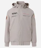 Campera rompevientos color beige con capucha, cierre frontal y bolsillos laterales. Presenta estampado de la NASA en el pecho, parche circular en la manga derecha y bandera de Estados Unidos en la manga izquierda.