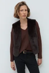 Chaleco reversible de corte recto, con un lado de cuero sintético color chocolate y el otro lado de piel sintética al tono. Presenta cuello redondo y diseño sin mangas.