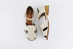 Sandalias bajas de cuero color crudo, con tiras entrecruzadas en el empeine, pulsera con hebilla al tobillo, punta almendrada y taco cuadrado de madera.