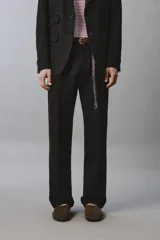 Pantalón de vestir regular fit confeccionado en lino, con pliegues frontales, bolsillos laterales y bolsillos traseros de doble vivo con botón. Presenta cierre frontal con cremallera y gancho metálico oculto.
