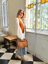 Cartera bandolera de cuero color camel, con forro interno de tela y flecos laterales.