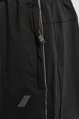 Pantalón jogger negro de corte regular, confeccionado en tejido técnico con algodón. Presenta cintura elástica ajustable con cordón interior, bolsillos laterales y puños elásticos en los tobillos. Posee un pequeño logo estampado en contraste en la pierna derecha.