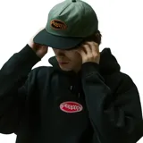 Gorra de visera plana con corona color verde militar y visera negra. Presenta un parche ovalado frontal con el logo 'Former' bordado en color naranja sobre fondo negro.
