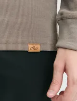 Remera de manga larga con cuello polo, confeccionada en tejido de punto canalé francés. Presenta abotonadura frontal con botones de madera y detalles a contratono en la cartera y el interior del cuello.