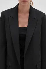 Blazer de corte holgado con diseño de rayas verticales, cuello solapa y cierre frontal con un botón. Presenta bolsillos laterales con solapa y mangas largas.