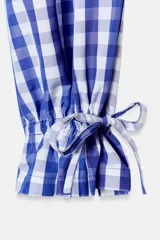 Pantalón de nylon con estampado de cuadros vichy azul y blanco. Presenta cintura elástica y bajo con volante fruncido y elástico.