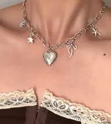 Collar tipo gargantilla de eslabones plateados con varios dijes colgantes: un relicario en forma de corazón, una flor, una estrella, un moño y una estrella de mar.