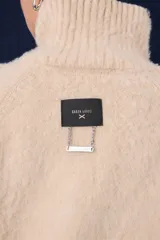 Polera de tejido suave con textura, cuello alto, mangas largas y silueta recta.