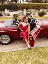 Vestido de fiesta fucsia con escote y espalda de cuero, tajos laterales con hilo metálico y terminación con flecos.