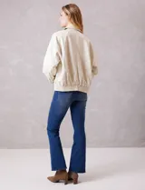 Campera bomber de eco cuero color beige, con cuello camisero, cierre frontal metálico y bolsillos delanteros con solapa y botón a presión. Presenta mangas largas con puños abotonados y ruedo trasero elastizado.