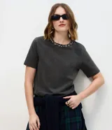 Remera de algodón con efecto de lavado desgastado, cuello redondo acanalado con aplicación de brillos y manga corta.