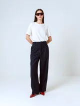 Pantalón de vestir negro con finas rayas verticales blancas, corte recto y tiro alto.