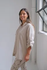 Campera tipo parka de color beige, con cierre frontal completo, capucha con cordones ajustables y mangas tres cuartos con detalle de trabilla y botón.