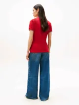 Chomba roja de algodón elástico con corte slim, cuello en V, tapeta abierta y mangas cortas con ribetes blancos y azul marino. Logo de Tommy Hilfiger bordado en el pecho.