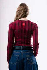 Top de tejido de punto ajustado al cuerpo, con diseño de rayas verticales en tonos bordó y rojo. Presenta cuello redondo y mangas largas.