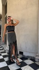 Falda asimétrica de tejido lurex negro y dorado, con pretina elástica y apliques de crochet en el ruedo.