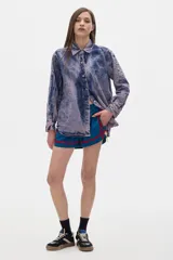 Camisa de jean azul con lavado gastado, corte oversized, manga larga y cierre frontal con botones.