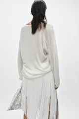 Jersey de punto fino negro con escote en V pronunciado, mangas largas y corte holgado con bajo asimétrico, más largo en la parte trasera.