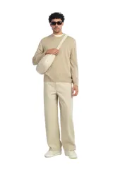 Bolso de hombro de tejido color beige, con diseño tipo medialuna, asa larga y cierre de cremallera.