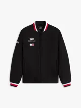 Campera estilo bomber de Tommy Hilfiger en colaboración con Cadillac Formula 1® Team, color negro. Cuenta con cuello tipo béisbol, cierre frontal de cremallera y ribetes tejidos a rayas rojas, blancas y azules en el cuello, puños y dobladillo. Presenta parches bordados del equipo en el pecho.