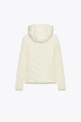 Cazadora acolchada color marrón con capucha ajustable, cuello subido y cierre frontal de cremallera. Presenta diseño combinado con mangas largas de tejido liso y cuerpo acolchado con costuras en chevrón, además de bolsillos laterales con cierre invisible.