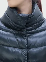 Campera larga de nylon color azul marino, con relleno de plumas, cuello alto y cierre con botones a presión.