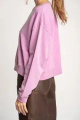 Buzo lila oversize confeccionado en 100% algodón, con cuello redondo, mangas largas y puños y dobladillo acanalados. Presenta un pequeño detalle bordado en el bajo.
