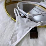 Set de lencería de cuatro piezas compuesto por bralette de encaje, tanga regulable, portaligas y ligas. Confeccionado en microtul y encaje con transparencias.