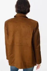 Chaqueta de gamuza color marrón con solapas clásicas, cierre frontal de botones y bolsillos laterales. Presenta un corte recto y estructurado.