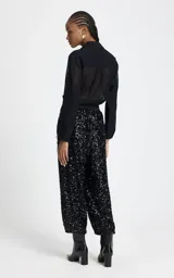 Pantalon de corte recto y holgado, confeccionado en tejido cubierto de lentejuelas negras. Presenta una cinturilla elástica ancha en contraste, bolsillos laterales con cierre y diseño de tiro alto.