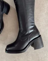 Bota de caña alta color negro, de cuero vegano, con punta cuadrada y taco bloque.