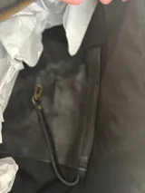 Bolso de hombro grande de cuero negro, con correa ancha y bolsillo interno con cierre.