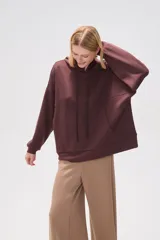 Canguro negro holgado con capucha y cordones ajustables, mangas largas y bolsillos laterales.