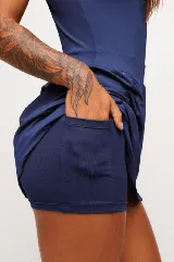 Vestido deportivo negro sin mangas, con escote en V y logo estampado en el pecho. Falda corta con short interno y bolsillos laterales. Incluye protección UV50+.