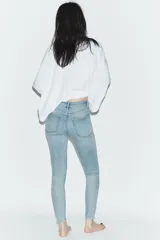 Jeans skinny de tiro alto y largo al tobillo, confeccionados en tejido super elástico con diseño de cinco bolsillos, cierre frontal con cremallera y botón metálico.