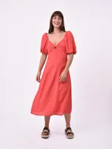 Vestido midi de color coral, con escote corazón, detalle de nudo en el centro del busto y mangas cortas abullonadas.