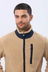 Campera de corderito con interior de polar, cuello alto y cierre frontal. Presenta un bolsillo vertical con cierre en el pecho, bolsillos laterales y detalles de ribete en contraste.