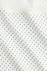 Top corto ajustado de punto, color blanco con pequeños lunares oscuros. Presenta escote Bardot (hombros descubiertos) y ribetes de encaje en el escote y los bordes de las mangas cortas.