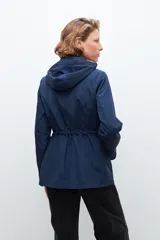 Campera impermeable azul marino con capucha desmontable, cierre frontal con botones a presión y cordón ajustable en la cintura.