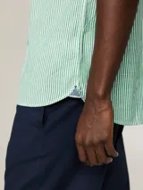 Camisa de manga corta Tommy Hilfiger de corte regular, confeccionada en popelín de algodón con Flex Technology y diseño de rayas verticales verdes y blancas. Cuenta con cuello abotonado y logo bordado en el pecho.