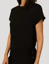 Conjunto de dos piezas compuesto por una remera de manga corta con cuello redondo y frunces laterales ajustables, y un pantalón de corte ancho con cintura elástica y bolsillos laterales.