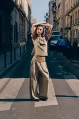 Pantalón de algodón color beige con tiro medio, cintura elástica ajustable con cordón y perneras anchas con pliegues delanteros y bolsillos laterales.