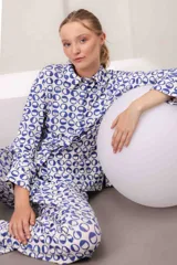 Conjunto de pijama de dos piezas con estampado geométrico en azul y blanco. Incluye una camisa de manga larga con cuello y botones frontales, y un pantalón largo a juego.