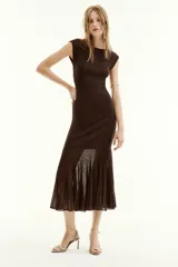 Vestido midi de punto color marrón, sin mangas, con cuello redondo y diseño ajustado que presenta el bajo con acabado plisado.