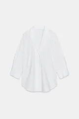 Camisa de algodón con cuello solapa y escote en pico, mangas tres cuartos con puños anchos y bajo redondeado asimétrico.