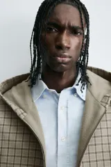 Cazadora boxy fit de algodón con estampado de cuadros en tonos beige y gris. Presenta cuello con capucha, cierre frontal de cremallera, mangas largas con puños elásticos y bolsillos frontales tipo canguro.