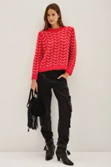 Sweater de punto con diseño de patrón geométrico en colores rojo y blanco, cuello redondo y mangas largas.