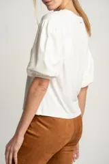 Remera blanca de manga corta abullonada con textura de puntos en relieve, escote redondo y calce holgado.