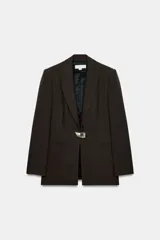 Blazer entallada de cuello solapa y manga larga con hombreras. Presenta bolsillos delanteros de vivo y cierre frontal con un botón metálico decorativo.