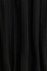 Vestido corto negro sin mangas de punto suave con textura. Tiene cuello redondo, espalda superescotada, falda con leve vuelo y ribete festoneado en cuello y sisas.